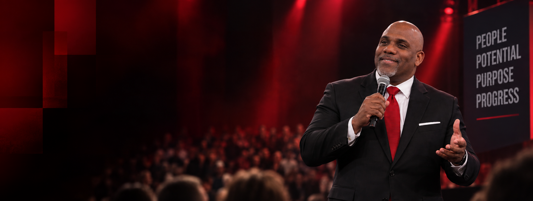 Jermaine Fletcher speaking on stage under red lights, addressing an audience