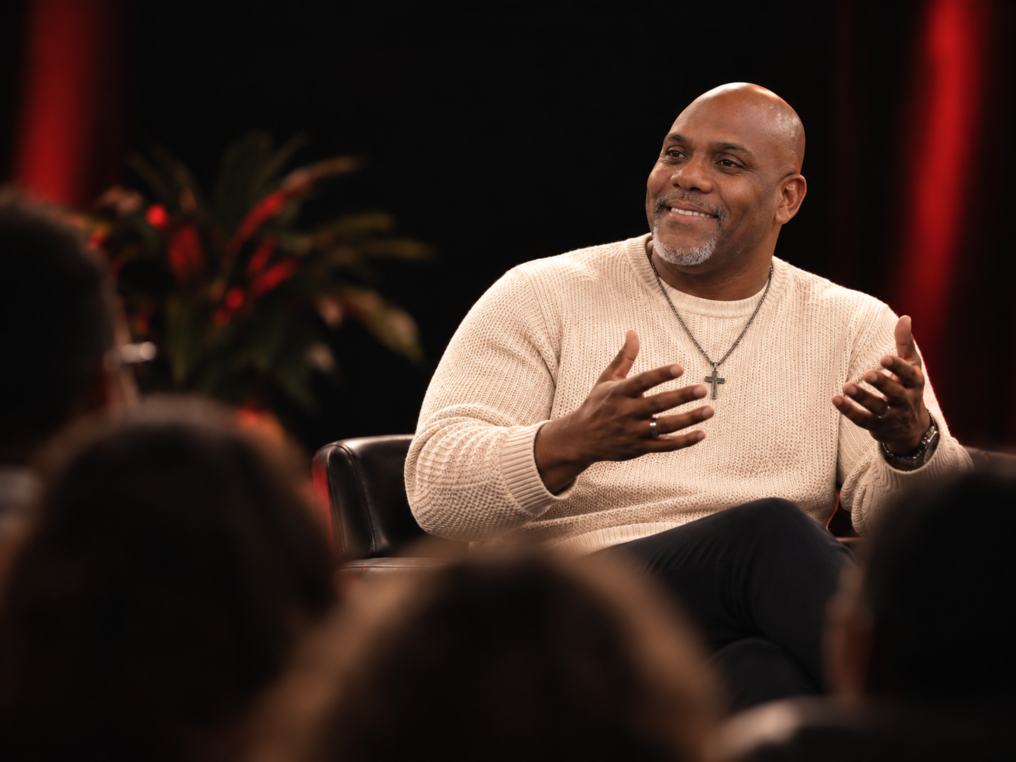 Jermaine Fletcher seated, mid-conversation in a warm cream sweater